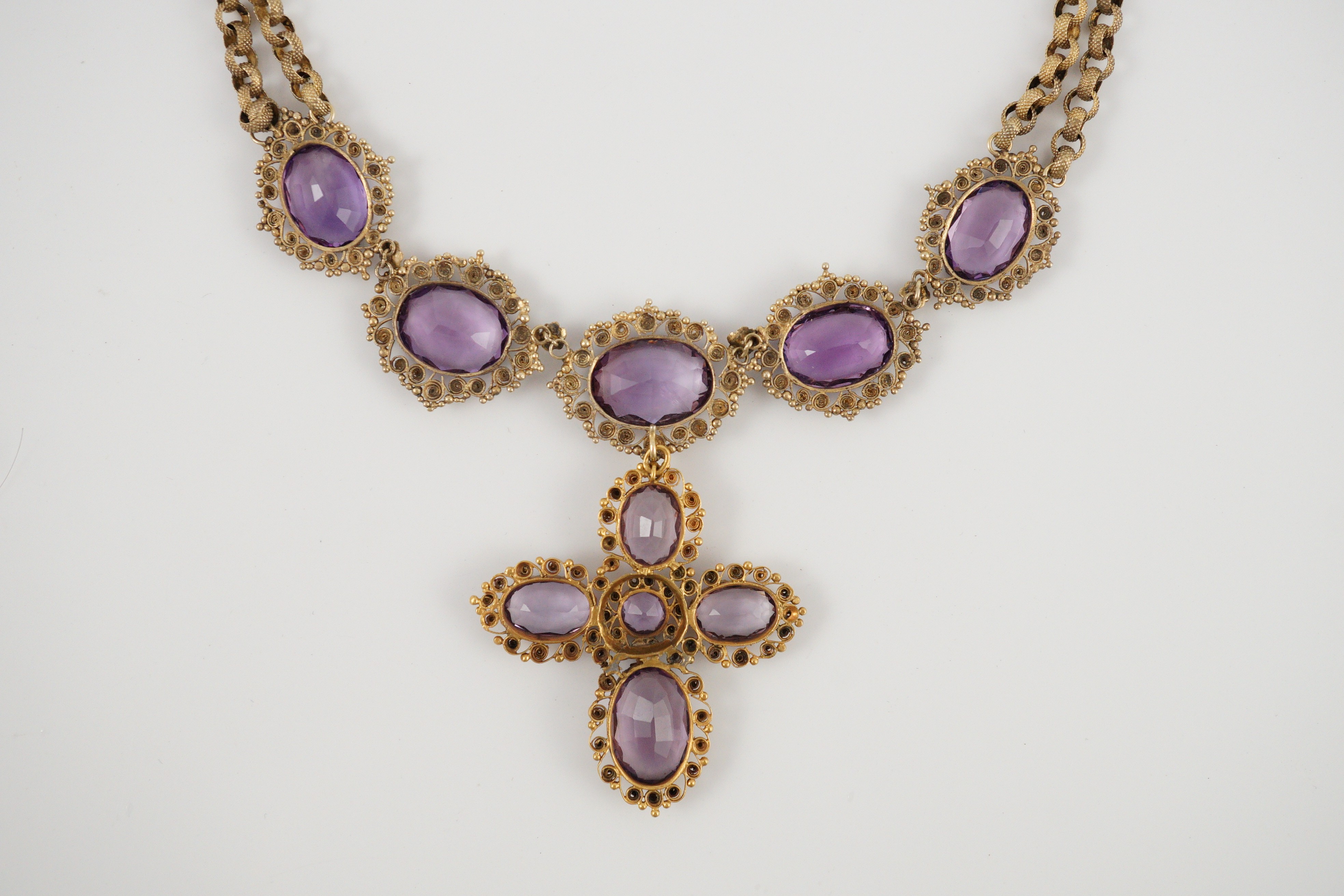 An early 19th century gold and eleven stone oval cut amethyst set pendant necklace and a similar cross pendant (repair)